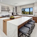 Rancho Santa Fe Lago Vista kitchen by Aranelli Design — double islands in walnut and marble with a full cooktop wall and window framing the valley