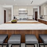 Rancho Santa Fe Lago Vista kitchen by Aranelli Design — straight-on view of the marble waterfall island with bench seating and walnut base cabinetry